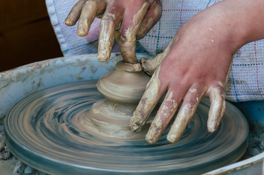 Hands shaping pottery during an activity